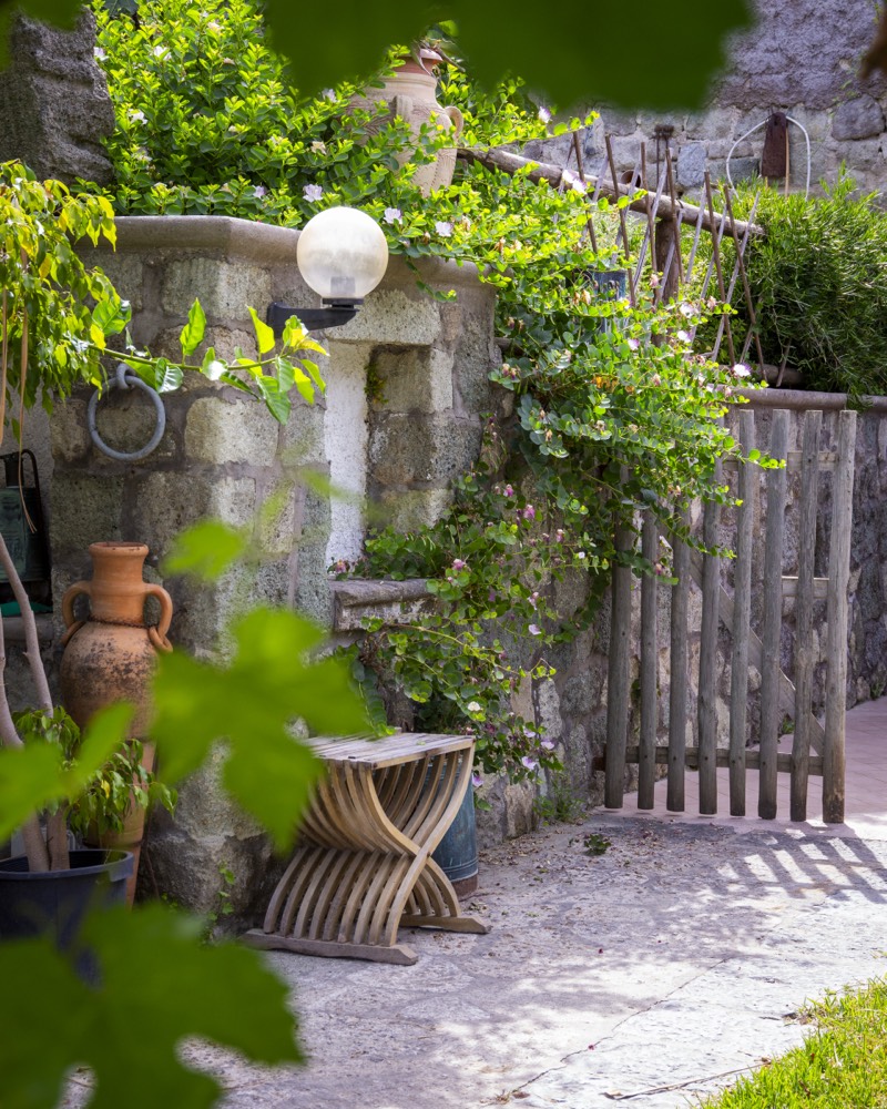 Angolo del giardino con pozzo in pietra e vasi di terracotta